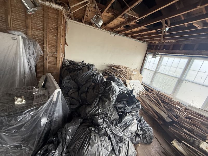 Interior tear-out with bagged debris and old lumber inside a room