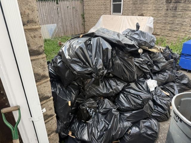Large pile of bagged junk and debris in a backyard ready for junk removal
