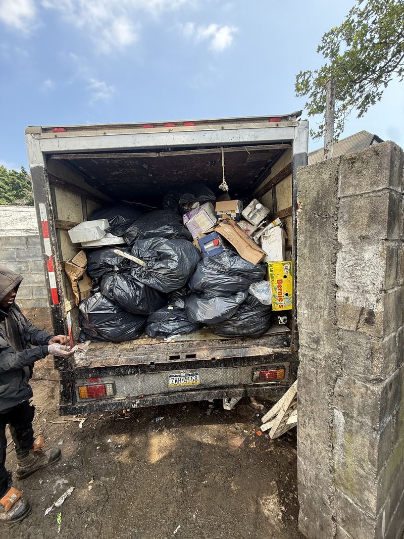 JR Hauling truck being loaded with bags of yard waste and junk