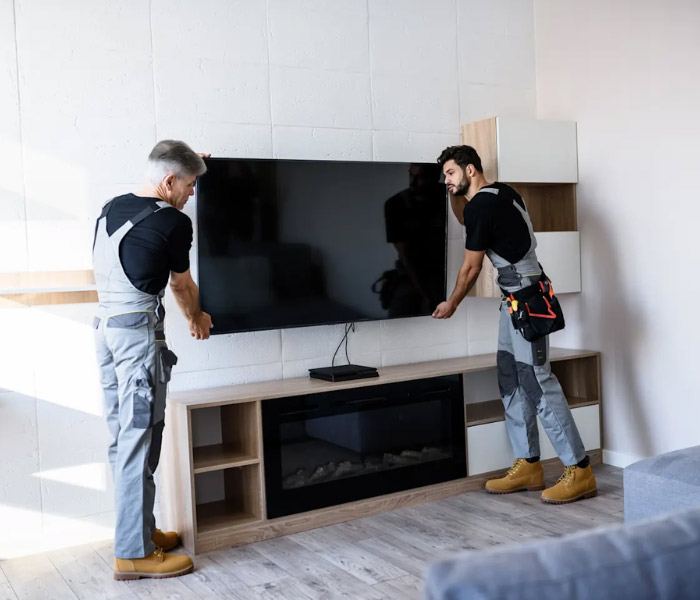 Two installers mounting a flat-screen TV level on a living room wall